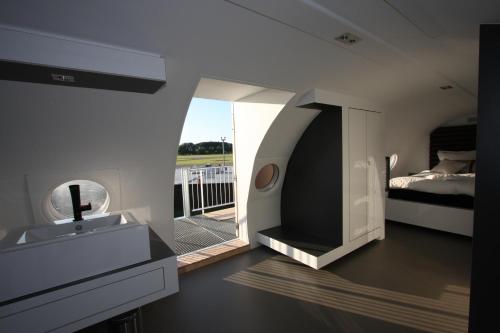 een badkamer met een wastafel en een slaapkamer met een bed bij Vliegtuigsuite Teuge in Teuge