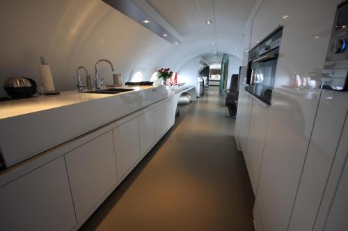 a kitchen with white cabinets and a long hallway at Vliegtuigsuite Teuge in Teuge