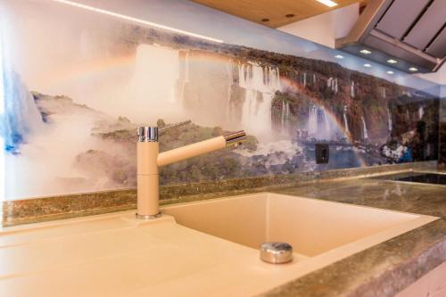 Wasserfall Moarlhof Kastelruth في كاستيلِروتّو: بالوعة الحمام مع لوحة الشلال على الحائط