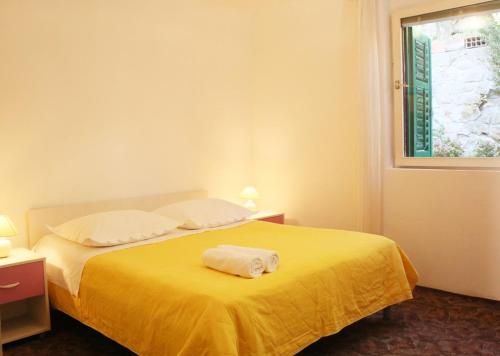 a bedroom with a yellow bed with two towels on it at Apartments Antonio in Baška Voda
