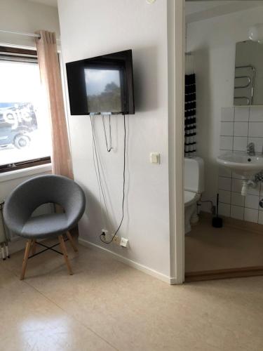 a bathroom with a chair and a television on a wall at Gotlands Idrottscenter Vandrarhem in Fårösund