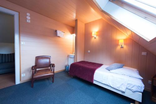 a bedroom with a bed and a chair in a room at Hotel SPA Au Cheval Blanc in Ribeauvillé