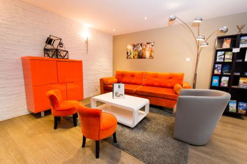 a living room with an orange couch and chairs at Hotel SPA Au Cheval Blanc in Ribeauvillé