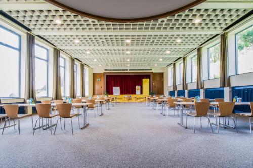 a large room with tables and chairs and windows at JUFA Hotel Königswinter/Bonn in Königswinter