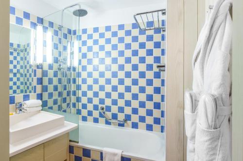 uma casa de banho com um lavatório e um chuveiro com azulejos azuis e brancos. em SOWELL HOTELS Le Beach em Trouville-sur-Mer