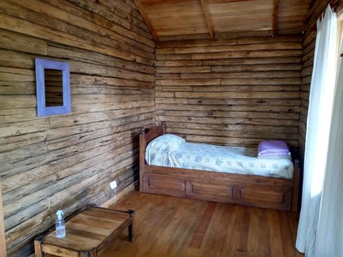 Cabaña de madera con cama en una habitación en Cabañas Artemisa en Tandil
