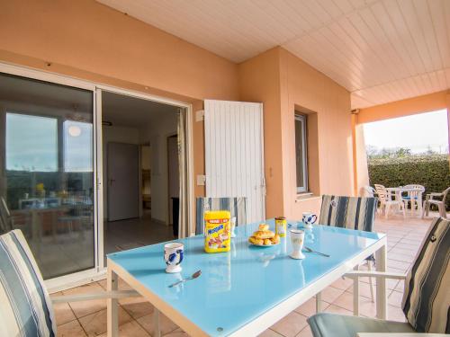 une table bleue avec une assiette de nourriture sur une terrasse dans l'établissement Apartment Les Rives du Lac-5 by Interhome, au Grau-du-Roi