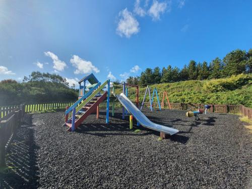 a playground with a slide on a hill at Hustyns Resort Cornwall in Wadebridge
