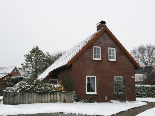 ein rotes Backsteinhaus mit Schnee auf dem Boden in der Unterkunft Holiday Home Riedehuus by Interhome in Norddeich