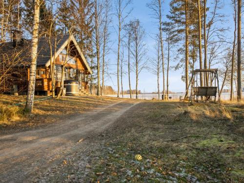 uma cabana de madeira na floresta ao lado de uma estrada de terra em Holiday Home Huvilakoti 1 by Interhome em Puromäki