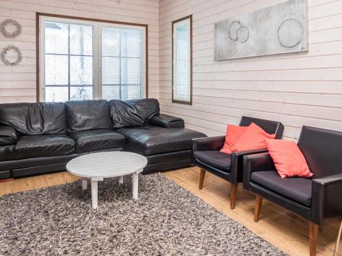 ein Wohnzimmer mit einem schwarzen Ledersofa und Stühlen in der Unterkunft Holiday Home Saukkotupa by Interhome in Ruka
