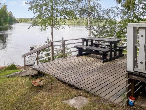 a picnic table and bench on a wooden dock near a lake at Holiday Home Piilopirtti by Interhome in Juhanala