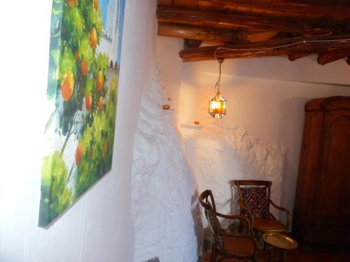 Casita de la Vaca في Mondújar: غرفة بها لوحة على الحائط وكرسي