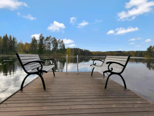 PetäjävesiにあるHoliday Home Kuusikumpu by Interhomeの三つのベンチが湖畔の桟橋に座っている