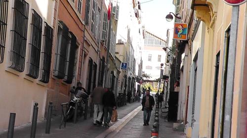 um grupo de pessoas andando por uma rua estreita em Hôtel de la Renaissance em Marselha