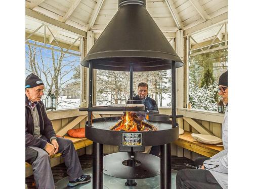 Dois homens sentados à volta de uma fogueira num fogão. em Holiday Home Päätalo by Interhome em Vääksy