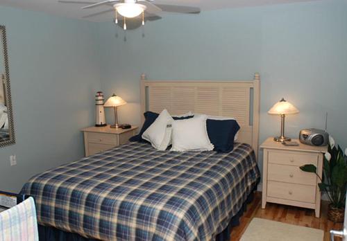 a bedroom with a bed with a blue and white plaid blanket at Auberge Bay Wind Suites in Chéticamp