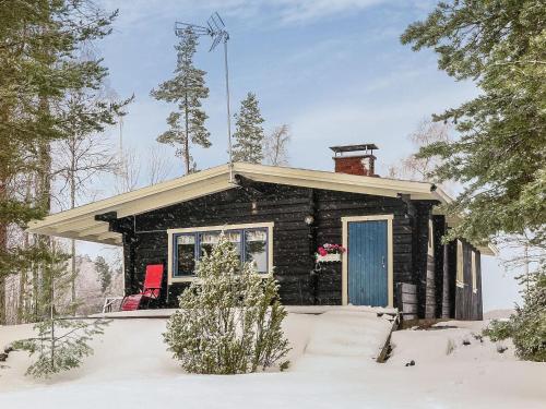 uma cabana de madeira na neve com uma porta azul em Holiday Home Inninniemi by Interhome em Pyhäsalmi