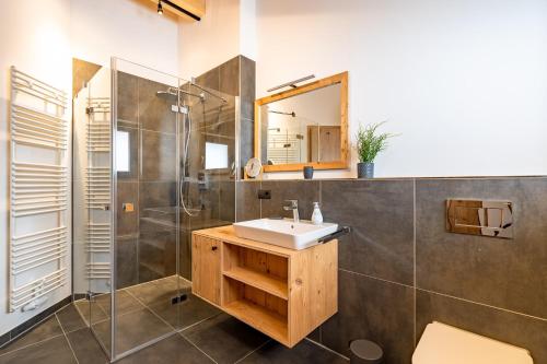 a bathroom with a sink and a shower and a mirror at Chalet Allgäublick in Sonthofen