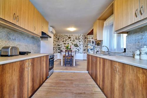 a kitchen with wooden cabinets and a kitchen with a table at Maria's cozy stonehouse in Kerames