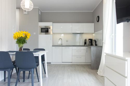 a kitchen with white cabinets and a table and chairs at Komfortowy Apartament Lazur z garażem in Kołobrzeg