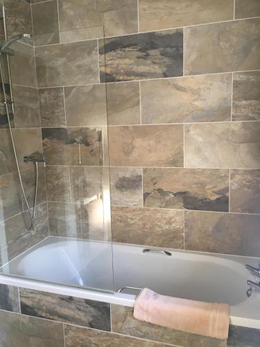 a bath tub in a bathroom with a tile wall at The Kings Head in Louth