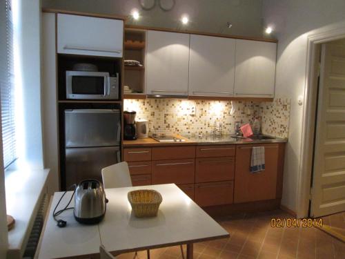 a kitchen with white cabinets and a table and a microwave at Apartments Hotel Rivoli Jardin in Helsinki