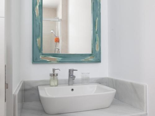La salle de bains est pourvue d'un lavabo blanc et d'un miroir. dans l'établissement La Fontanilla Place, à Conil de la Frontera