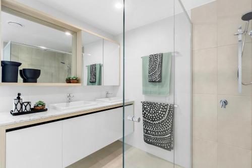 a bathroom with a glass shower and a sink at Koko Broadbeach in Gold Coast