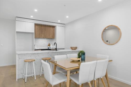 a kitchen with a wooden table and white chairs at Koko Broadbeach in Gold Coast
