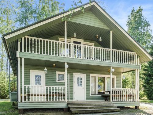 a green house with a porch and a balcony at Holiday Home Kesäranta by Interhome in Simanala