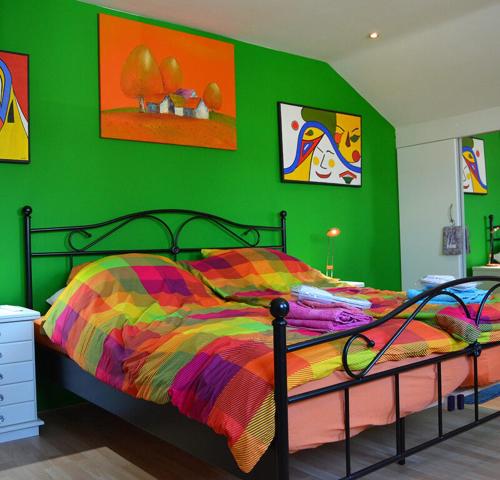 een groene slaapkamer met een bed met een kleurrijk dekbed bij Harry's Home Tiel Bed & Breakfast in Tiel