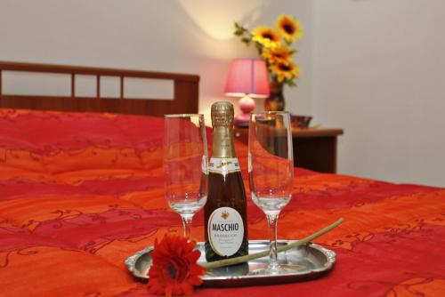 a bottle of champagne and two glasses on a bed at B&B Agorà a 2 minuti dalla Valle dei Templi e 5 minuti dal mare in Agrigento