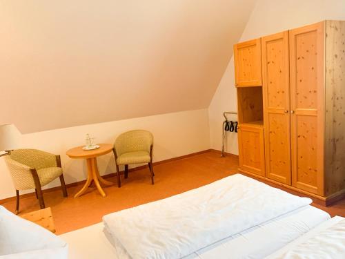 a bedroom with a bed and a table and chairs at Landhotel Bauernschmitt in Pottenstein