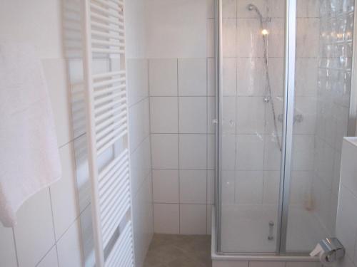 a shower in a bathroom with white tiles at Central Wohnen in Wilhelmshaven