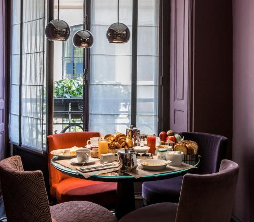 a table with breakfast food on it in a room with a window at Hôtel Mansart - Esprit de France in Paris