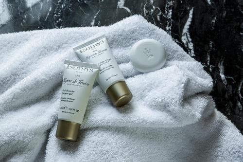two tubes of lipstick and a moisturizing cream on a towel at Hôtel Mansart - Esprit de France in Paris
