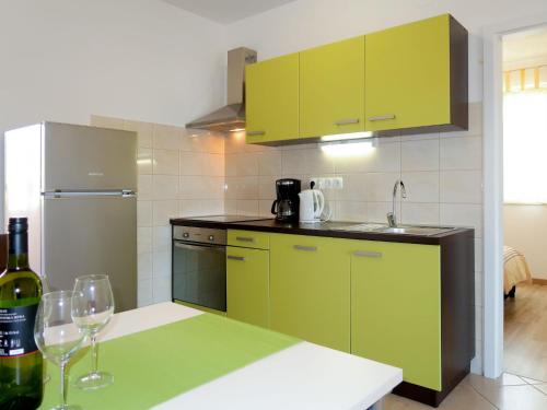 kuchnia z zielonymi szafkami i butelką wina w obiekcie Apartment Rosić - KRK217 by Interhome w mieście Kornić