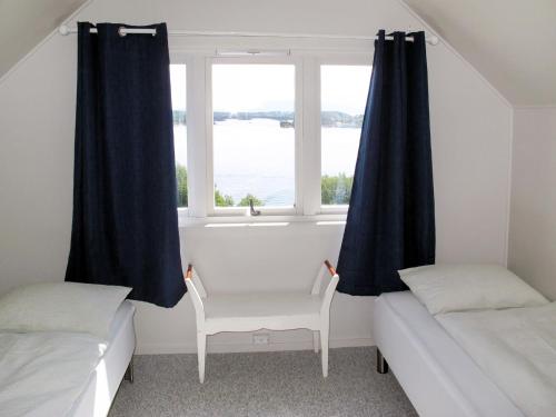 a room with two beds and a window with a chair at Holiday Home Strøneneset by Interhome in Hagavik