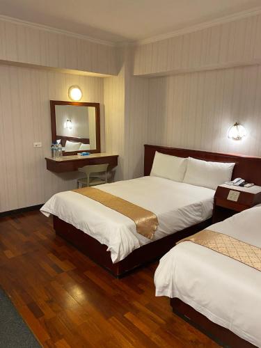 a hotel room with two beds and a mirror at Gene Long Haiy Att Hotel in Chiayi City