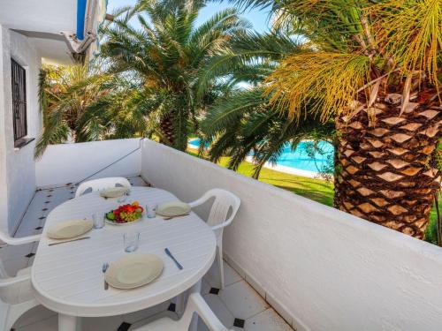 een witte tafel en stoelen op een balkon met palmbomen bij Apartment Ducado Golf CII by Interhome in Pals