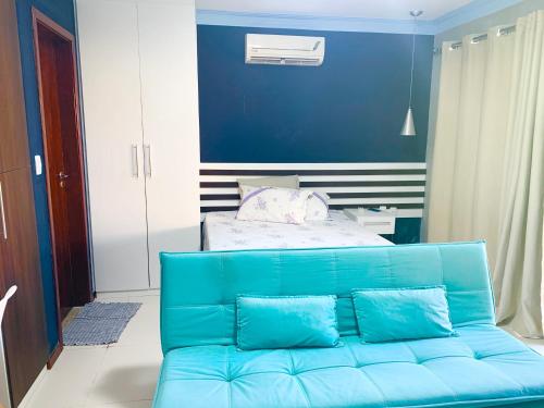 - un canapé bleu dans une chambre avec un lit dans l'établissement VILLAS DO PRATAGY, à Maceió
