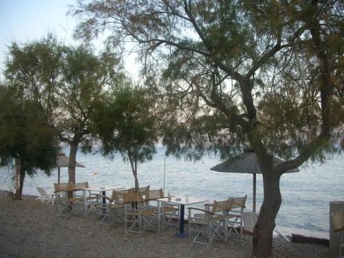 a table with chairs and an umbrella next to the water at Star Hotel in Nafpaktos