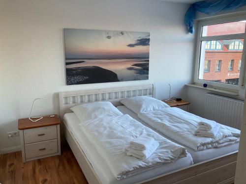 een slaapkamer met 2 bedden en een foto aan de muur bij Hellinghaus FeWo 3 Strandläufer in Wyk auf Föhr