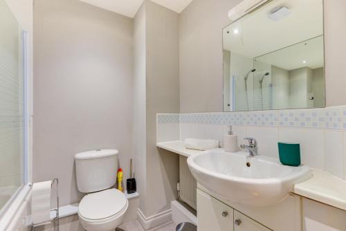 een badkamer met een toilet, een wastafel en een spiegel bij GF flat sleeps 4, parking for Contractors by Eagle Owl Stays in Crawley