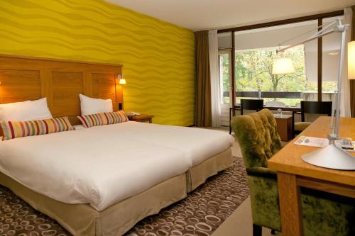 a hotel room with a large bed and a desk at Fletcher Hotel Restaurant Sallandse Heuvelrug in Rijssen