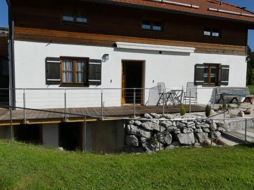 a white house with a deck and a porch at Ferienwohnung Max Fegg in Anger