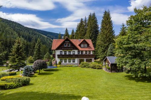 a large house on a green lawn with trees at Hotel Resort Martin & Kristyna in Špindlerův Mlýn