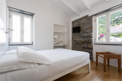 a white bedroom with a large bed and windows at La Malà - camere di charme in Vernazza