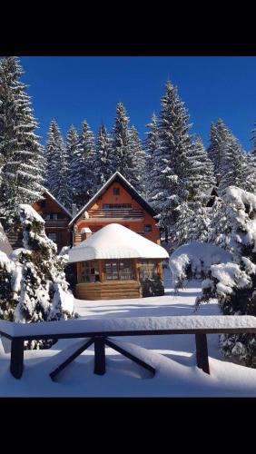 a log cabin in the snow with a bench in front at Apartmani Megara Vlasic in Šišava